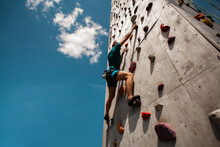 Sportsman Climber On Steep Rock, Climbing On Artificial Wall. Extreme Sports And Bouldering Concept.