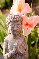 Sticker - Vertical shallow focus closeup shot of stone Buddha statue with closed eyes near pink Lupine flowers