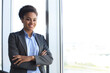 © ty - Attractive african american business woman looking at camera and smiling while standing in the office.