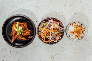 Wall Mural - Top view of a bowl of vegetables, white rice, and meat on a white table