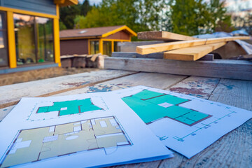 Drawings on the background of a wooden house. Construction of cottages. Floor plan near the lumber. Drawings at a construction site. Concept - preparation of lumber for construction.