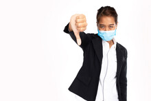Asian Businesswoman Wearing Surgical Face Mask In Formal Black Suit Jacket, Show Hand Thumps Down, Looking At Camera, Studio Lighting Isolated On White Background, Coronavirus, COVID-19 Concept