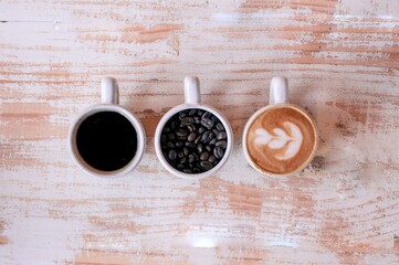 Sticker - High angle shot of three cups of different coffee on a wooden surface