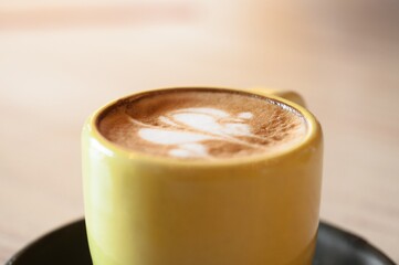 Sticker - Selective focus shot of a cup of coffee with latte art on a wooden surface