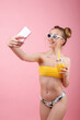 © BartLoveyou - girl in a swimsuit and glasses with a glass of juice takes a selfie on the phone. summer mood