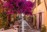 Fototapeta Uliczki - Nafplio - Greece. (june 2020). A typical street scene in the old town with vivid bougainvillea, shops, restaurants,  and cobbled streets.