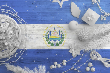 Wall Mural - El Salvador flag on wooden table with snow objects. Christmas and new year background, celebration national concept with white decor.