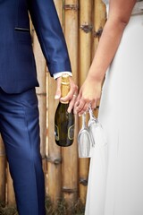 Poster - Bride and the groom holding a bottle of champagne and glasses