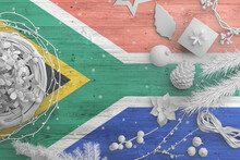 South Africa Flag On Wooden Table With Snow Objects. Christmas And New Year Background, Celebration National Concept With White Decor.