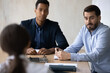 © fizkes - Two diverse hr manager listening to candidate at job interview, sitting at table, making decision about hiring, African American and Caucasian businessmen interns at meeting with mentor coach