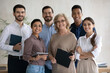 © fizkes - Corporate portrait smiling diverse employees team standing in office, looking at camera, successful happy workers with middle aged leader posing for photo, motivated staff, workforce