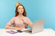 I am leader, big boss. Proud self-confident authoritative businesswoman wearing crown on head and pointing herself, looking with arrogance to camera. indoor studio shot isolated on blue background