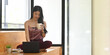 © Prathankarnpap - Young Asian woman is relaxing with a computer laptop while sitting on a wooden bench.