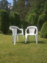 Two White Plastic Chairs Stand On The Lawn, Garden Furniture

