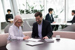 © fizkes - Senior happy business woman sign contract making deal with partner making investment. Elderly lady meeting with insurance agent, financial advisor or banker. Successful customer and client agreement