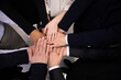 © fizkes - Multiracial business people stacking hands together top angle view. Close up pile of african american and caucasian hands of successful team of workers. Teamwork and unity concept