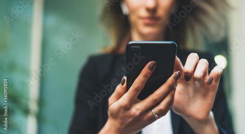 Fotomural Beautiful young business woman looking at her smart phone near corporate building