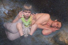 A 40-year-old European Man Lies And Sleeps. Gray Background. A 5 Year Old Boy Looks At His Hands. The Concept Of Entering The Astral World. Collage On The Theme Of Lucid Dreams.
