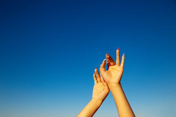 Woman hand on sky.Hands reaches for the sky.Young girl holding hands on blue sky background.Lifting hand to the sky