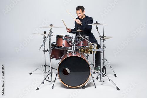 Fotografía Young attractive man drummer playing drums and cymbals isolated on white backgro