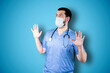 Doctor with mask over isolated blue background studio with surprise facial expression