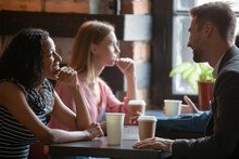 Multi ethnic couples sitting in cafe enjoy chatting, focus on African girl flirting with Caucasian guy during speed dating romantic meeting participation. Love seekers, romantic relationships concept