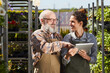 © Seventyfour - Waist up portrait of smiling senior farmer using digital tablet while instructing young female worker in plantation lit by sunlight, copy space