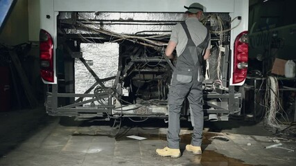 Wall Mural - Frustrated Mechanic Trying To Unsuccessfully Troubleshoot Electrical Problems In Empty Space Of Bus Engine Compartment. 