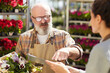 © Seventyfour - Portrait of bearded senior farmer instructing young worker and pointing at digital tablet while working in flower plantation, copy space