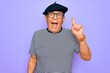 © Krakenimages.com - Senior handsome hoary man wearing french beret and glasses standing over purple background pointing finger up with successful idea. Exited and happy. Number one.