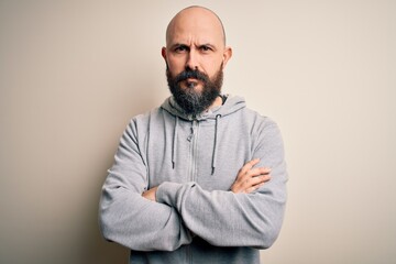 Sticker - Handsome sporty bald man with beard wearing sweatshirt standing over pink background skeptic and nervous, disapproving expression on face with crossed arms. Negative person.