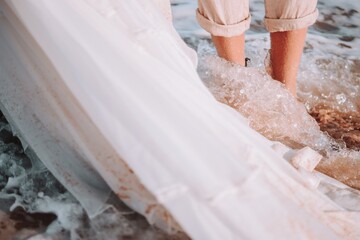 Sticker - Closeup shot of people standing in the wavy sea with white fabric on the side