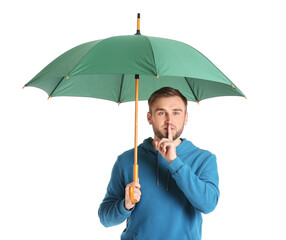 Canvas Print - Handsome young man with umbrella showing silence gesture on white background