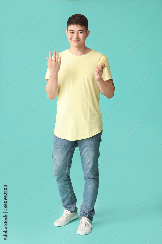 Asian man doing manicure on color background
