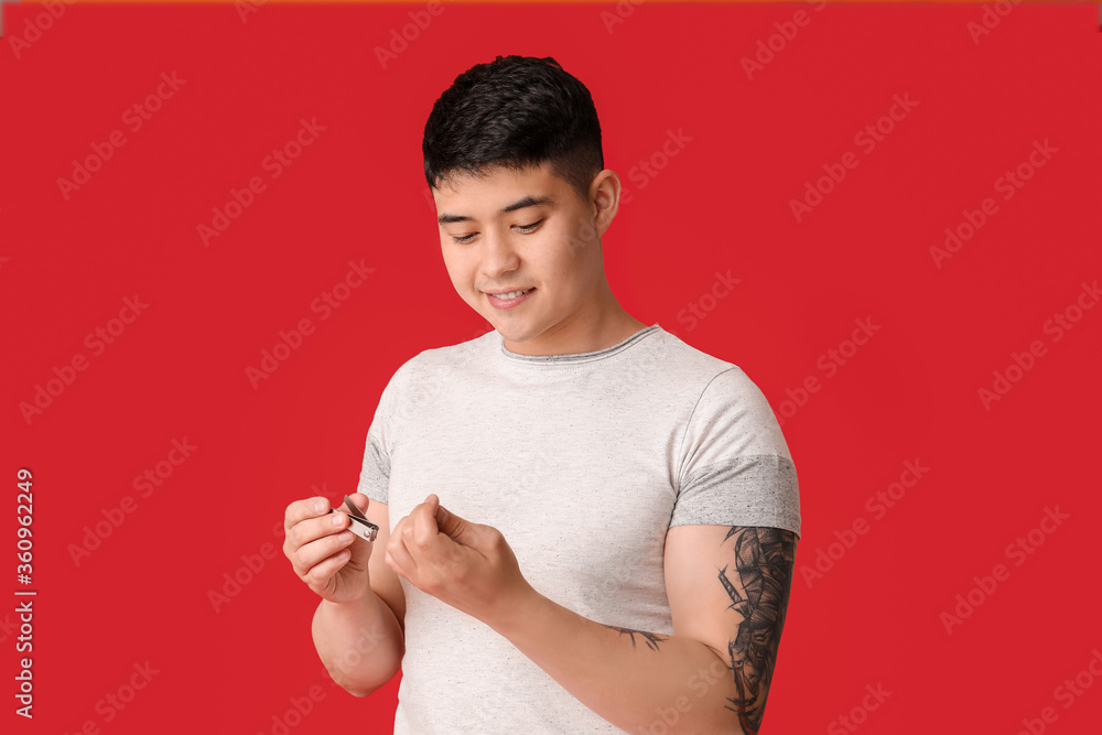 Asian man doing manicure on color background