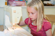 © dave - A young blonde girl using a sewing machine