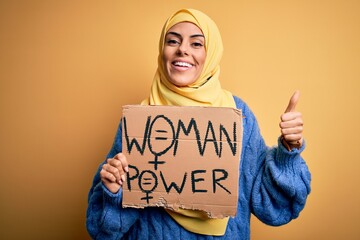 Sticker - Young beautiful arab woman wearing islamic hijab holding banner with women power message happy with big smile doing ok sign, thumb up with fingers, excellent sign