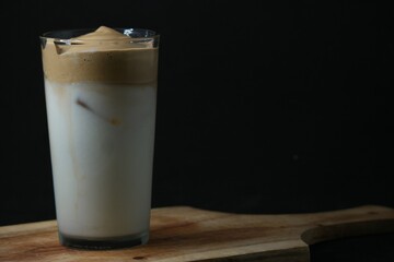 Sticker - Glass of white beverage with ice and beige crÃ¨me on top on the black background