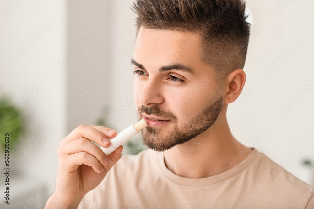 Handsome young man with lip balm at home