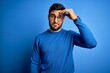 © Krakenimages.com - Young handsome man with beard wearing casual sweater and glasses over blue background worried and stressed about a problem with hand on forehead, nervous and anxious for crisis