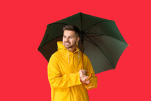 Young Man In Raincoat And With Umbrella On Color Background