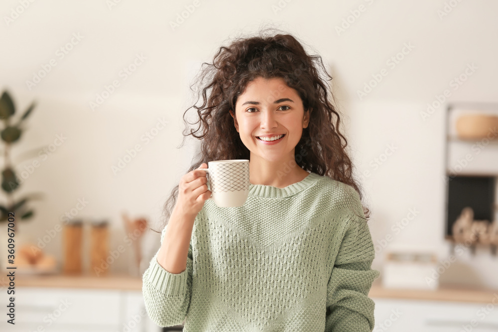 Beautiful young woman drinking hot tea at home