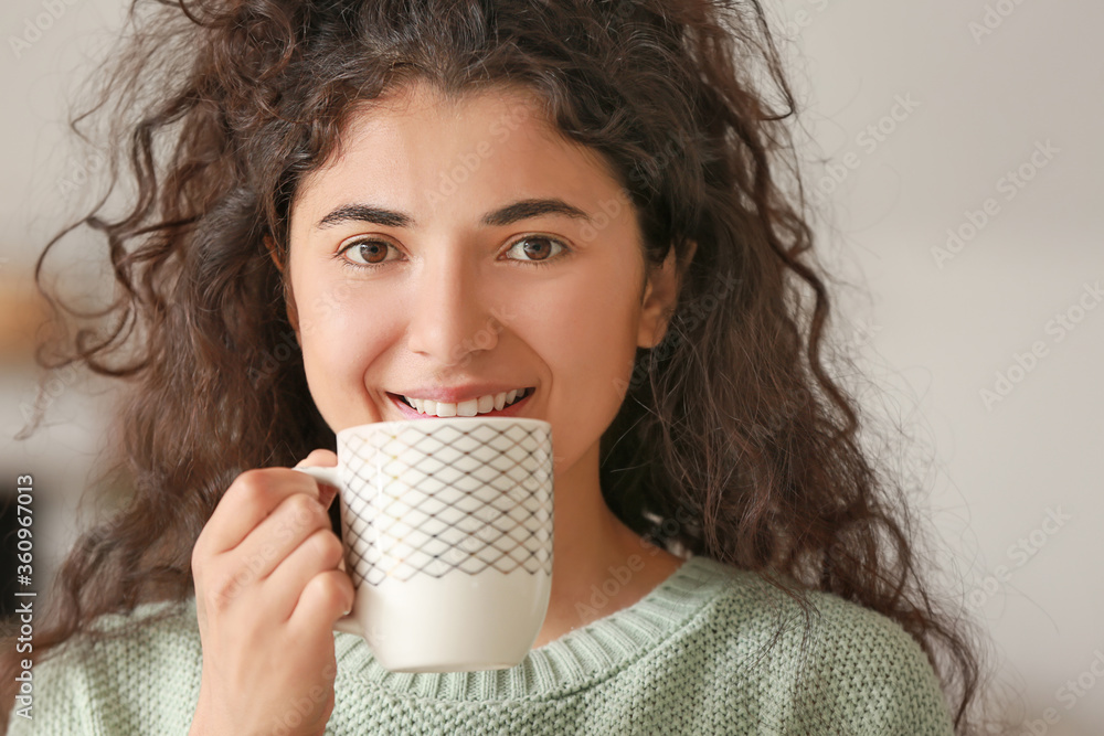 Beautiful young woman drinking hot tea at home