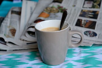 Wall Mural - Closeup of a cup of coffee against newspapers