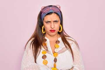 Canvas Print - Young hispanic hippie woman wearing fashion boho style and sunglasses over pink background skeptic and nervous, disapproving expression on face with crossed arms. Negative person.