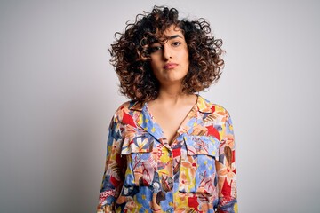 Poster - Young beautiful curly arab woman wearing floral colorful shirt standing over white background Relaxed with serious expression on face. Simple and natural looking at the camera.