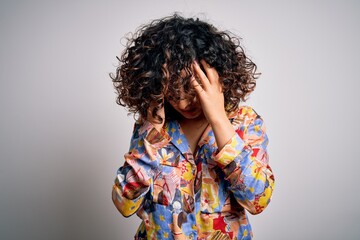 Wall Mural - Young beautiful curly arab woman wearing floral colorful shirt standing over white background with hand on head for pain in head because stress. Suffering migraine.