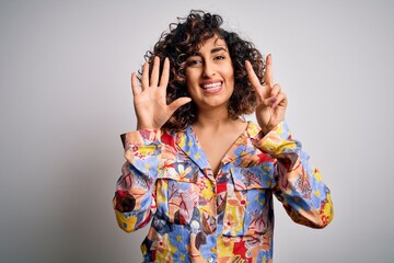 Sticker - Young beautiful curly arab woman wearing floral colorful shirt standing over white background showing and pointing up with fingers number seven while smiling confident and happy.