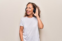Middle Age Beautiful Woman Listening To Music Using Headphones Over White Background Smiling With Hand Over Ear Listening And Hearing To Rumor Or Gossip. Deafness Concept.