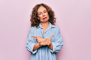 Poster - Middle age beautiful woman wearing casual denim shirt standing over pink background Pointing to both sides with fingers, different direction disagree